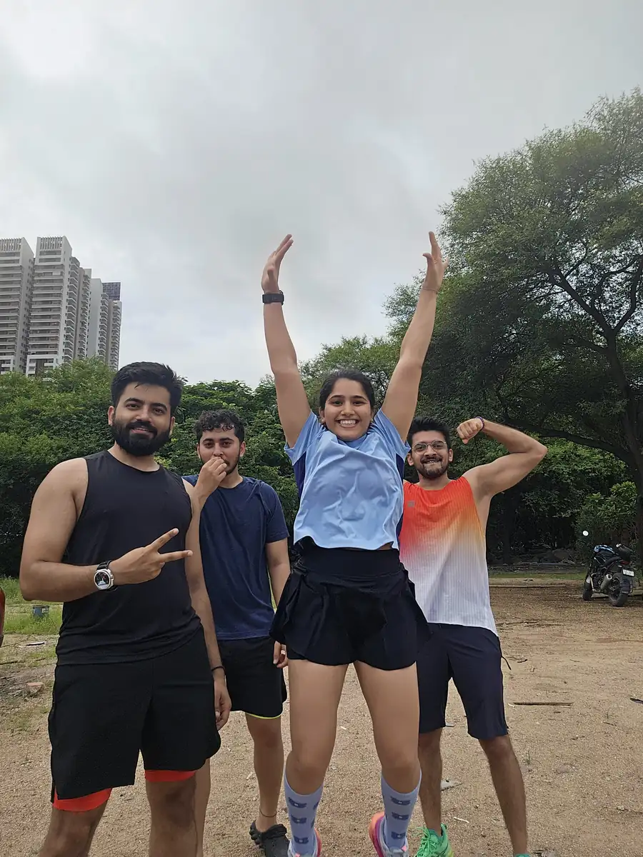 M³RC runners with arms raised after an early morning run, highrises behind
